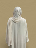 Back view of a woman wearing the Crush Jersey Hijab - Cocoon White with a light robe against a neutral background.